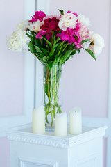 Bouquet of pink peonies on the vintage stand with candles