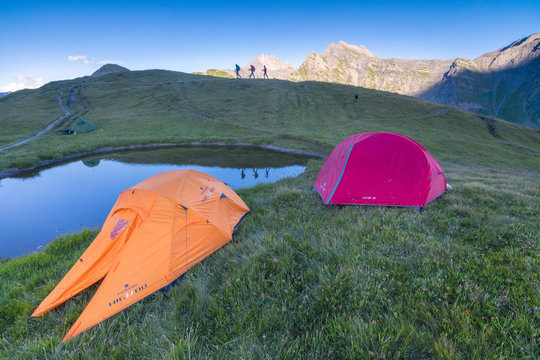 Camping tents and hikers with Mont De La Saxe on the background, Courmayeur, Aosta Valley