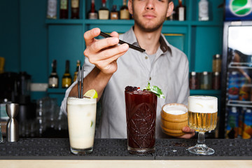 Young Barman offers cocktails in night club bar