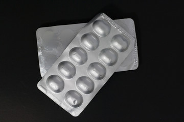 Closeup. Medication tablets packaged in a panel on a black background.