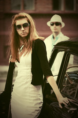 Young fashion woman in sunglasses next to vintage car