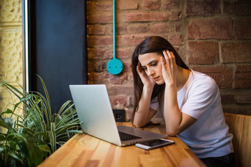 Shocked and sad woman holding computer, laptop tablet screen looking surprised in coffee shop