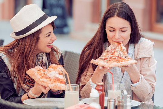 Two cheerful girls eating pizza
