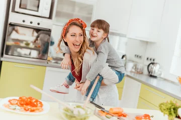 Wall murals Cooking Girl and mother cooking in the kitchen