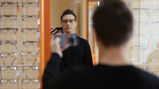 Man choosing new pair of glasses at optometrist