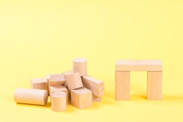 Obraz premium Wooden building blocks on yellow background.