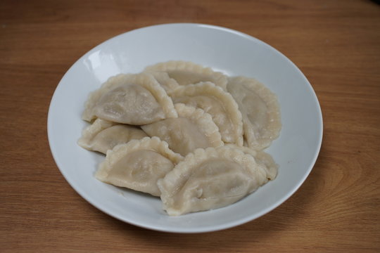 Boiled polish pierogs on the wooden brown table.