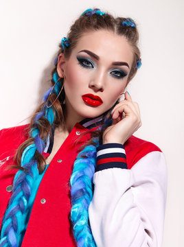 Beautiful young girl with long bright braids. Blue hair, weaving, Bright makeup, red jacket. Cosmetics. Photoshoot on a white background.