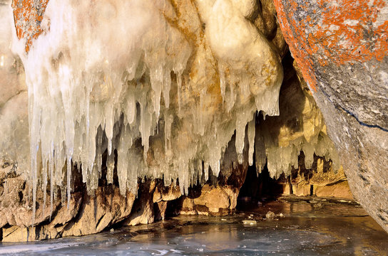 Icicles in the grotto on the shore of the Olkhon island in the rays of the rising sun. Lake Baikal