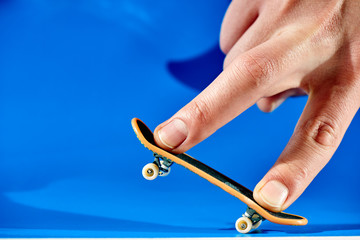 Men's fingers are doing the trick on fingerbone on a blue background closeup