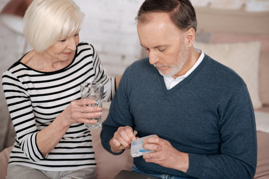 Old man going to take pills near his wife
