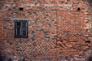 Old brick wall background including a little dark window
