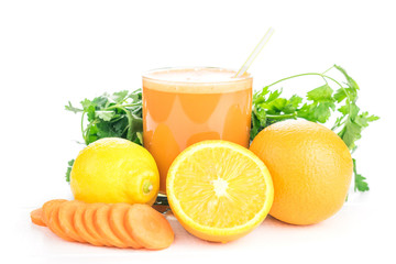 Carrot smoothie in a glass with fruits, on white wooden table.