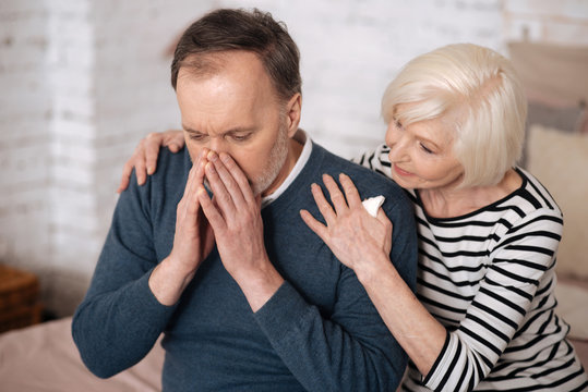 Elderly man sneezing near wife