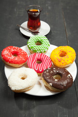 Cup of tea and donuts on a black wooden background