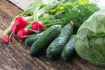 Fresh cucumbers onions radish and fennel on a wooden background