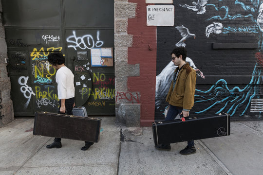 Young men carrying their guitar cases while walking outdoors