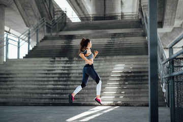 Fototapeta na wymiar Woman running in urban environment 