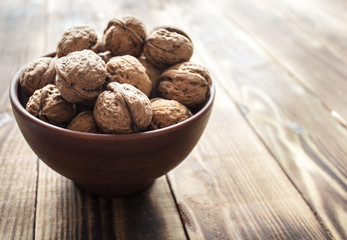 bowl with walnuts on wooden background