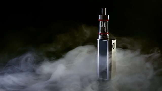 Electronic cigarette close-up on a black background in smoke