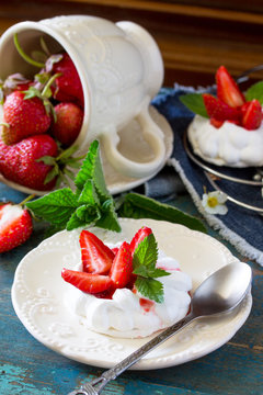Pavlova meringue pie with fresh strawberries on a vintage blue background.