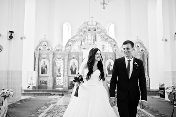 Happy wedding couple move at church, holding hands.