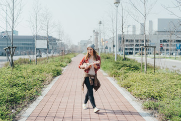Young woman walking in the city playing ukulele - busker, musician, composer concept