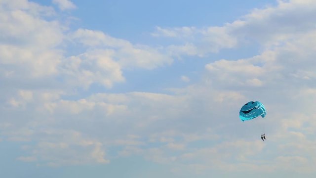 People flying on parachute in blue sky. Parasailing. Real time full hd video footage.
