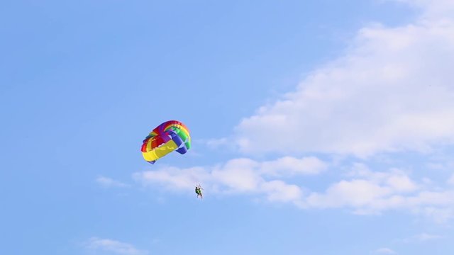 People flying with parachute in blue sky. Parasailing. Real time full hd video footage.