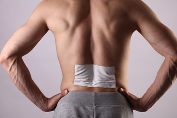Obraz premium Medicated pain relief patch, plaster. man with back pain. Pain relief and health care concept.