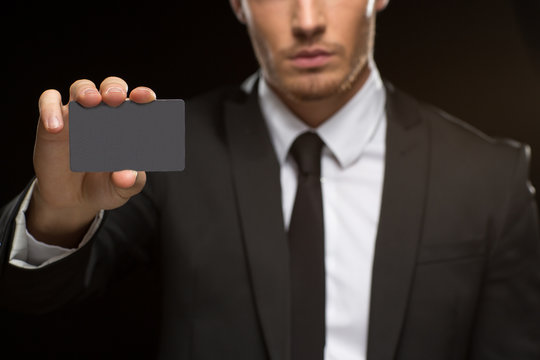 Handsome businessman holding a black card with a copyspace on