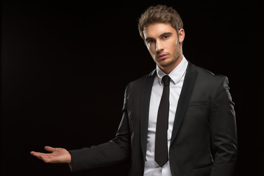 Serious handsome businessman in a suit on black background