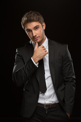 Sexy young suited man posing on black background