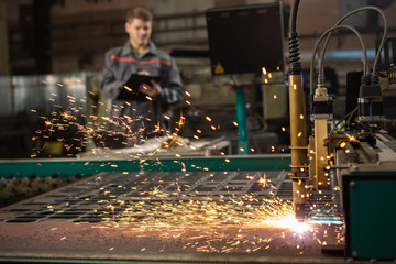 Industrial worker operating plasma cutter at the metal factory