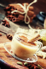 Masala tea with milk and spices on a vintage wooden background, selective focus