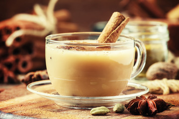 Masala tea with milk and spices on a vintage wooden background, selective focus