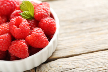 Red raspberries in bowl on a grey wooden table