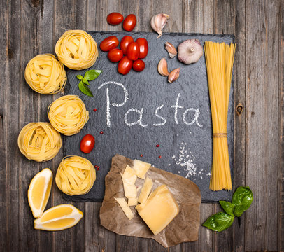 Pasta background with ingredients for cooking on slate board, top view.