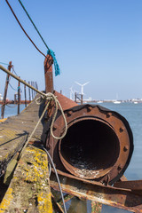 Abandoned harbor sewer front of wind turbine on the seaside of Isle of Sheppey England United-Kingdom