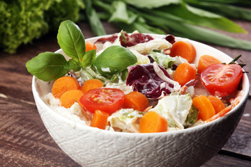 bowl of salad with vegetables and greens on wooden table