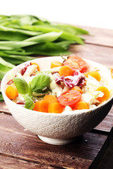 bowl of salad with vegetables and greens on wooden table