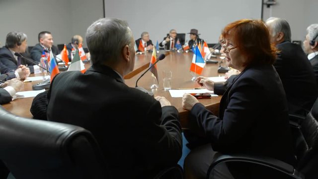 Close shot of US and Germany delegates comfortable and friendly talk at the round table of international meeting.
