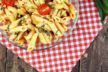 Penne pasta in tomato sauce with chicken, tomatoes decorated with basil on a wooden table