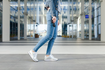 Detail of a woman's legs, in motion. Young woman wearing jeans, dynamic view. Outdoor concept for modern outdoor or lifestyle activities. 