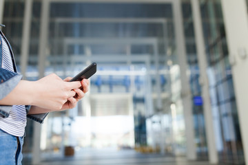 Close-up of female hands using modern smart phone, outside in daylight. Girl typing text message on her cellphone