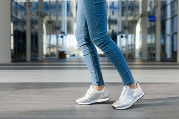 Detail of a woman's legs, in motion. Young woman wearing jeans, dynamic view. Outdoor concept for modern outdoor or lifestyle activities.