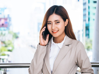 Fototapeta premium Portrait of a business woman in a suit talking on cellphone outdoors.