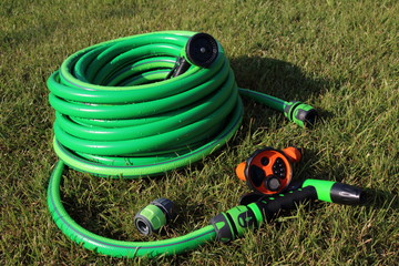 Garden hose bundle, connector and various adjustable showers (spray) on the mown lawn in the summer...