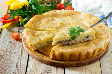 A classic quiche Lorraine pie with potatoes, cabbage, fish and cheese on a wooden table. Place for the text.