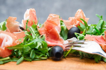 chopping board with aragula and raw ham